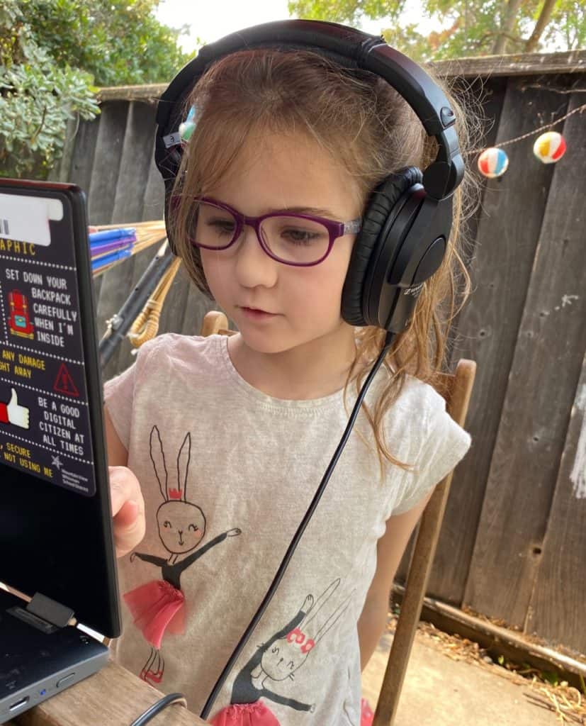 Lulu doing remote school in front of her chromebook in the backyard